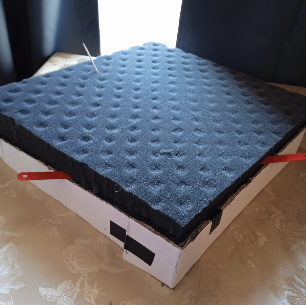 Hacksaw blade cutting through foam block at an angle guided by cardboard mold edges